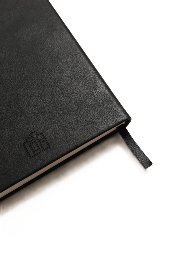 Close-up of black leather journal cover showing textured finish and minimal debossed logo detail.